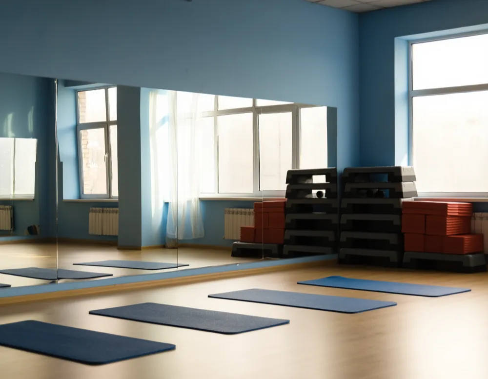 The course studio before a class: mats laid out on pale wood, a mirrored wall, stacked step boxes