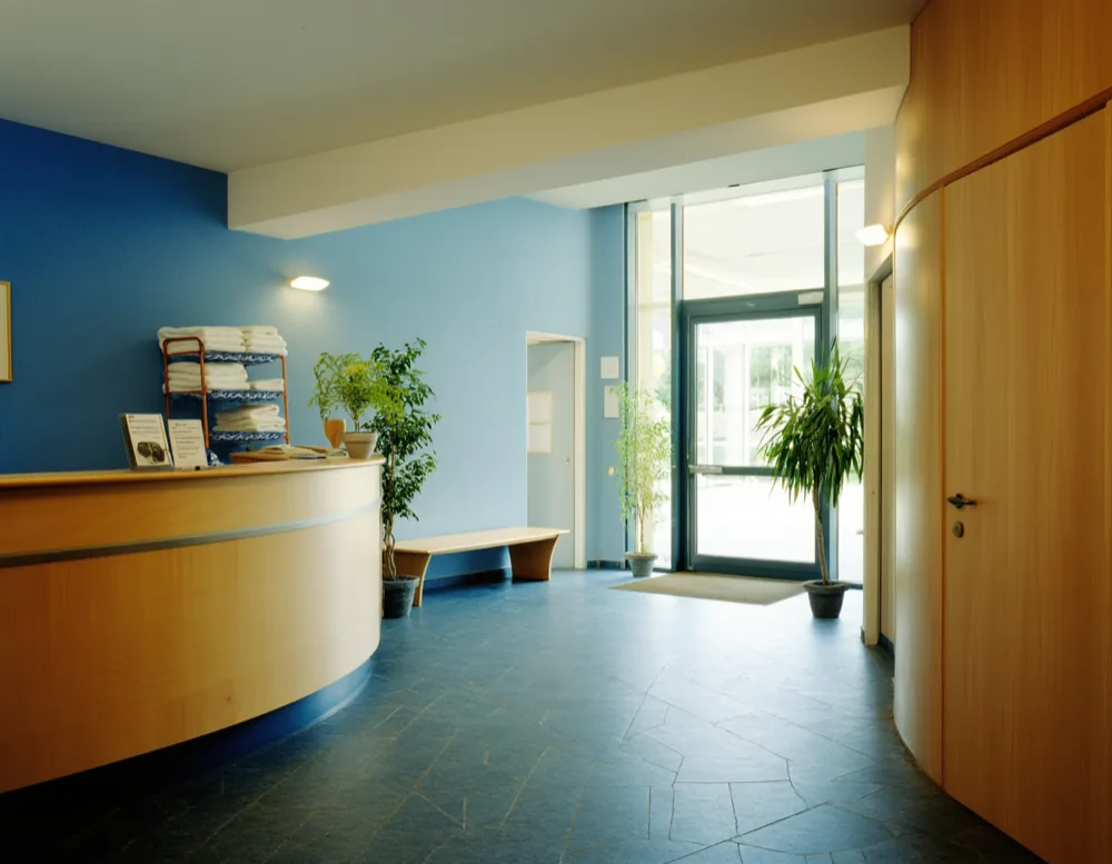 The entrance and reception counter in oak, with a bench and a corridor leading to the halls